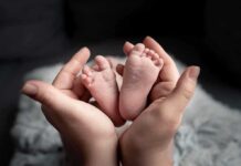 Baby feet cradled in adult hands.