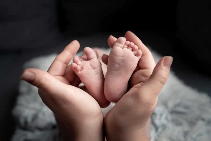 Baby feet cradled in adult hands.