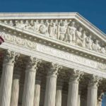 US Supreme Court building facade with flag.