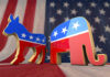 Donkey and elephant symbols with American flag background.