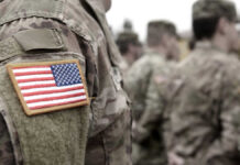 U.S. soldiers in camouflage uniforms with American flag patch.