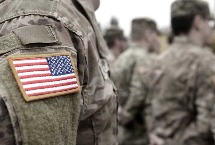 U.S. soldiers in camouflage uniforms with American flag patch.