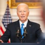 Joe Biden speaking at podium with American flag background