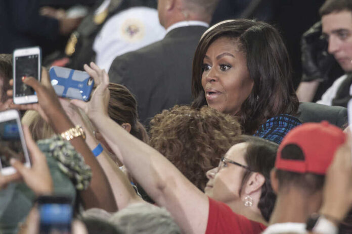 People taking photos with Michelle Obama in a crowd.