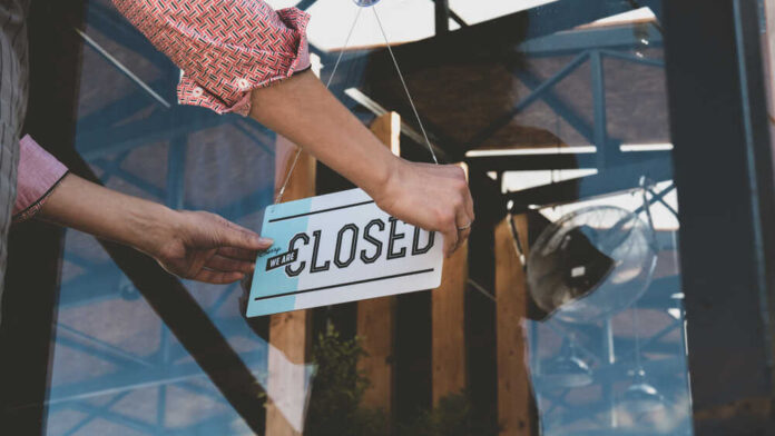 shutterstock_1162554778.jpg featured image Person flipping closed sign on glass door