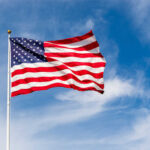 American flag waving against a blue sky.
