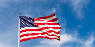 American flag waving against a blue sky.