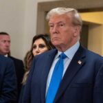Donald Trump in formal attire standing indoors.