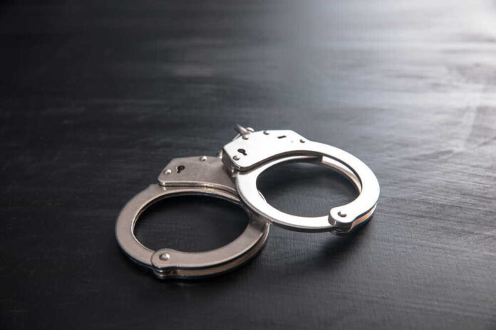 shutterstock_1857504991.jpg featured image Metal handcuffs on a dark textured surface.