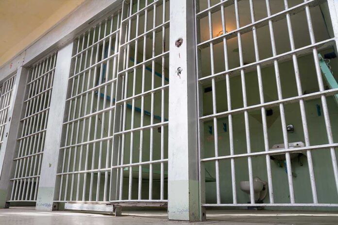556002781 featured image Empty prison cell with metal bars and toilet.
