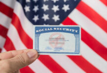 Hand holding social security card, American flag background.