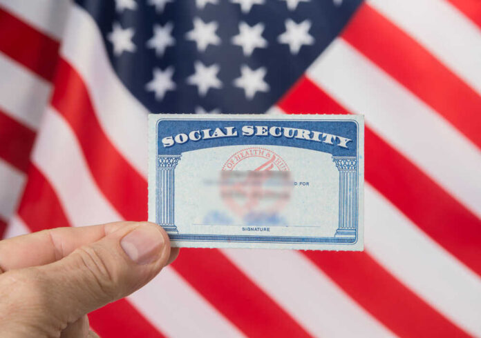 shutterstock_1125089156.jpg featured image Hand holding social security card, American flag background.