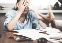 Stressed woman with hands on face at a desk.