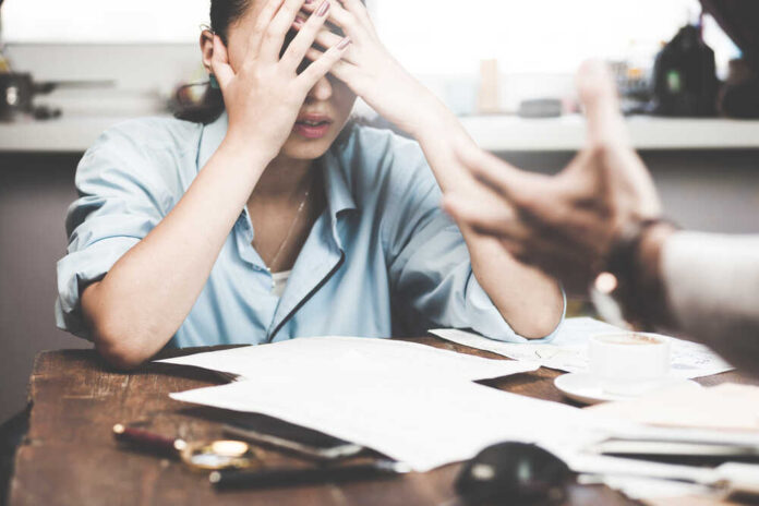 shutterstock_481953475.jpg featured image Stressed woman with hands on face at a desk.