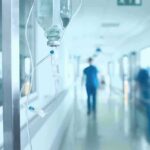 Hospital corridor with IV drip and healthcare worker.