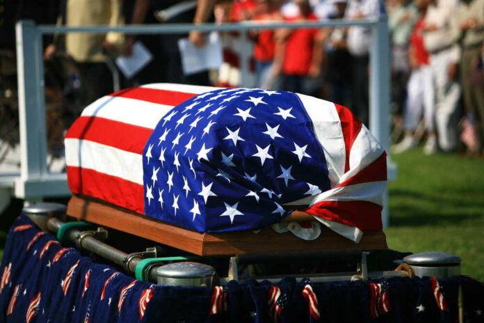 shutterstock_106701479.jpg featured image American flag draped over a casket at ceremony.