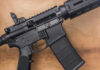 Black rifle on wooden surface close up