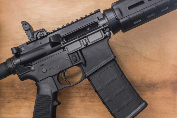 Black rifle on wooden surface close up