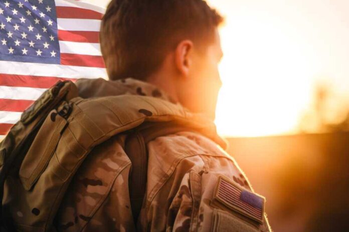 shutterstock_2283246601.jpg featured image Soldier in uniform with American flag at sunset.