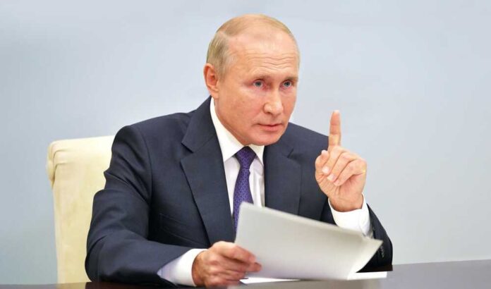 shutterstock_2329478645.jpg featured image Vladimir Putin, holding papers, in a meeting.