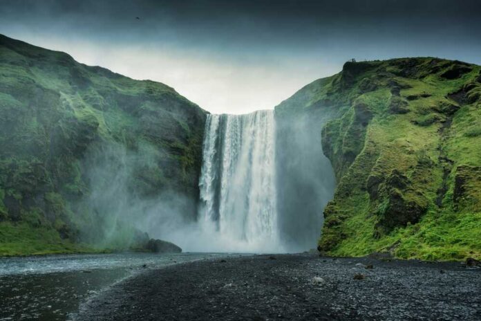 Waterfall cascading between lush green cliffs landscape