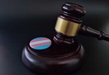 Gavel with transgender flag badge on black surface