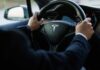 Person driving a Tesla car steering wheel