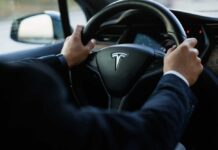 Person driving a Tesla car steering wheel