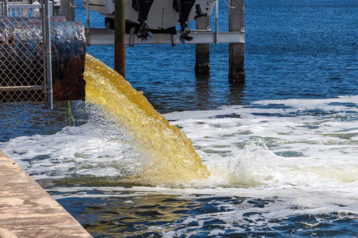 Water pipe discharging yellow liquid into ocean
