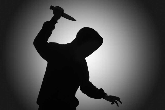 Silhouette of hooded figure holding a knife