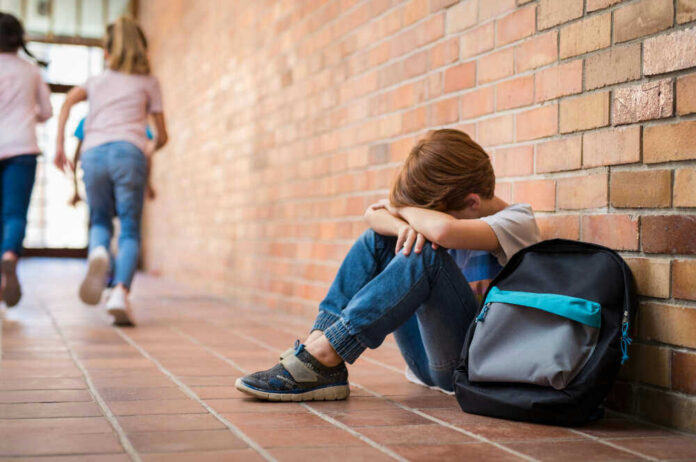 Sad child sitting against brick wall