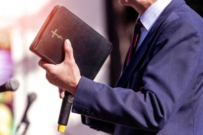 Man holding a Bible during a speech or presentation.