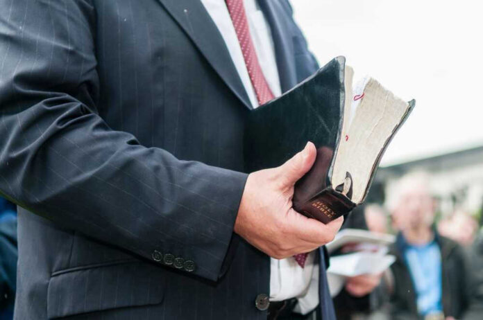 Man in suit holding a worn Bible