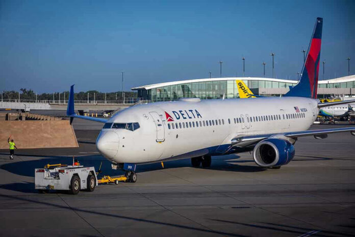 Delta airplane being towed at airport terminal gate