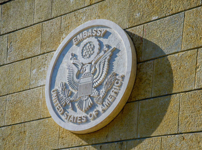 United States Embassy seal on a brick wall.