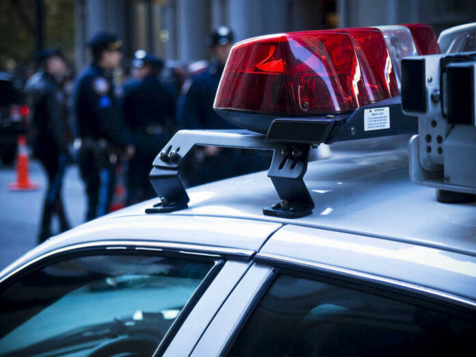 shutterstock_46269745.jpg Police car roof with lights, officers in background