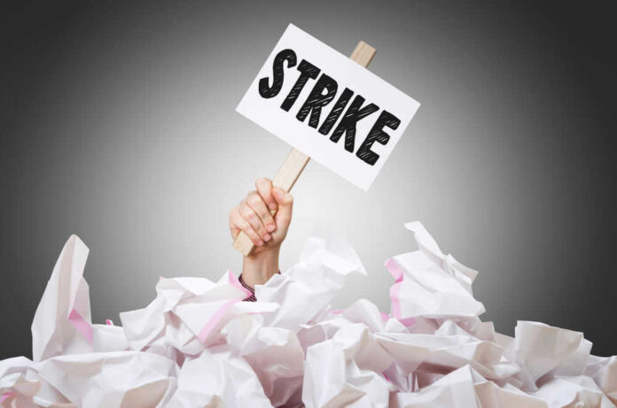 Hand holding strike sign amid crumpled paper pile