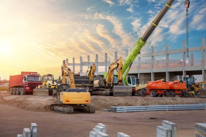 Construction site with various heavy machinery and a sunset sky