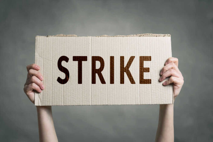 Two hands holding cardboard sign with strike text