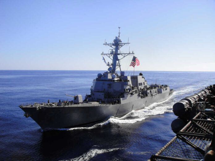 Warship with American flag sailing in the ocean.