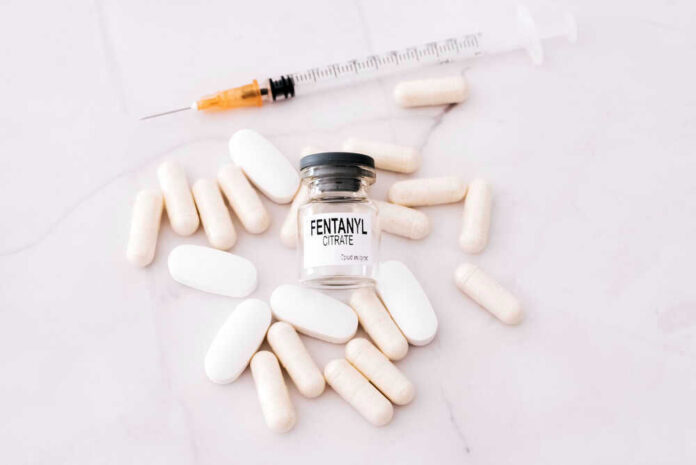 Fentanyl citrate vial surrounded by various pills and syringe.