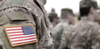 U.S. soldiers in camouflage uniforms with American flag patch.