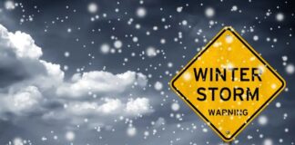 A yellow warning sign indicating a winter storm amidst falling snow
