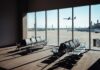 View of an airport waiting area with an airplane taking off in the background