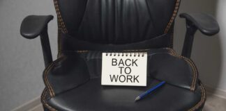 A black office chair with a notepad saying 'BACK TO WORK' and a blue pen on it