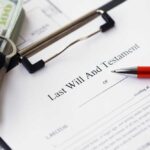A last will and testament document with a pen, keys, and cash