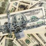 A stack of hundred dollar bills secured with a chain and padlock