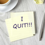 Note with I QUIT near coffee, pen, paper ball.