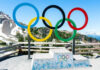 Olympic rings and podium with mountain backdrop.