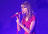 Taylor Swift in a red dress performing on stage.
